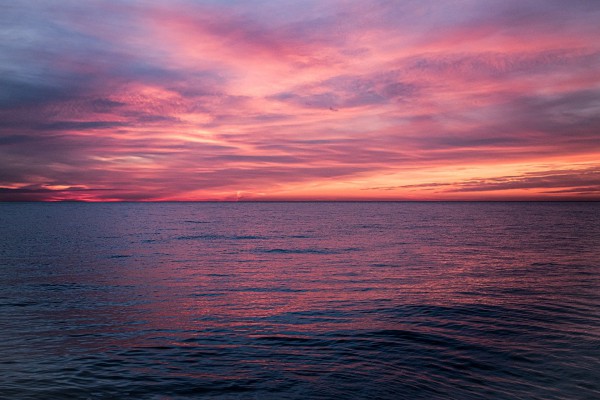 Morze | zachód słońca nad morze, chmury w odcieniach bieli i czerwieni, delikatne fale